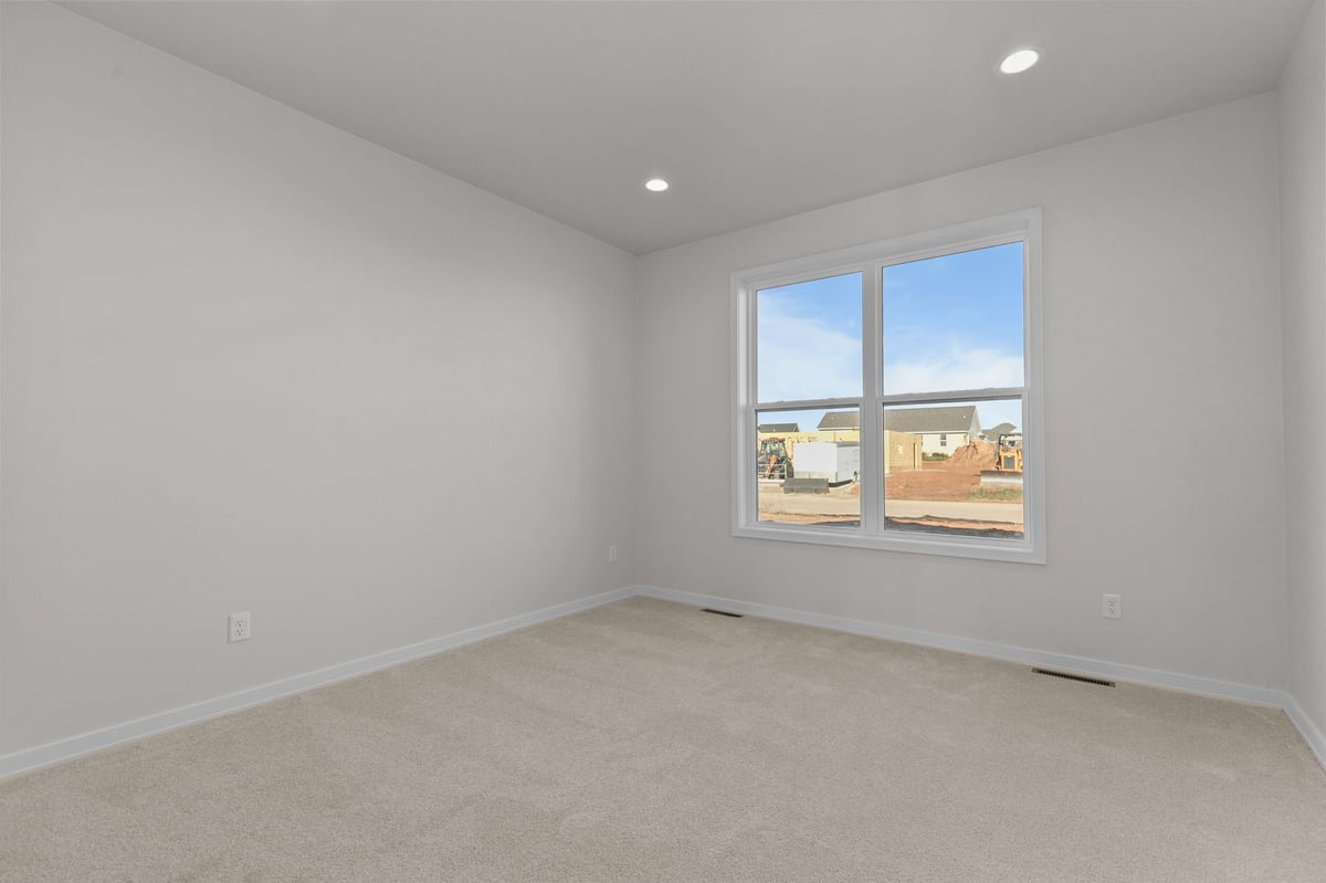 Appleton, WI bedroom with neutral carpet, large window, and view of new construction neighborhood