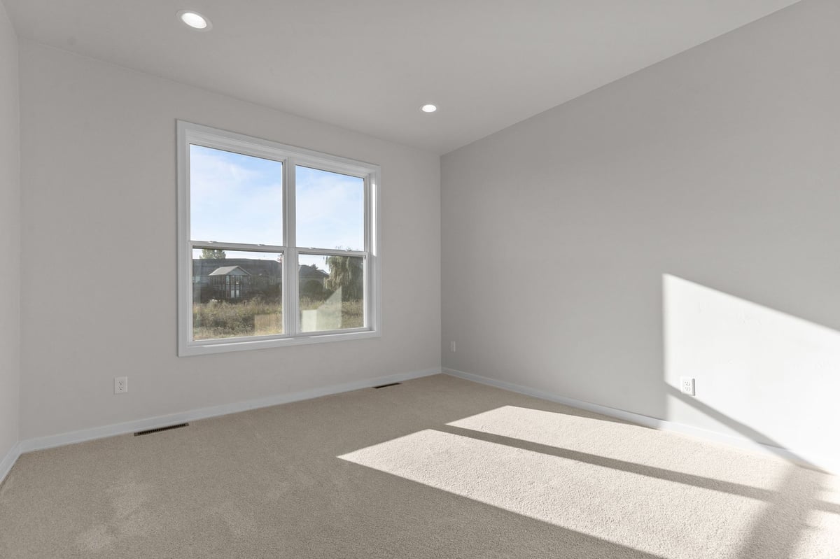 Appleton, WI bright bedroom with carpet, white walls, large window, and natural sunlight