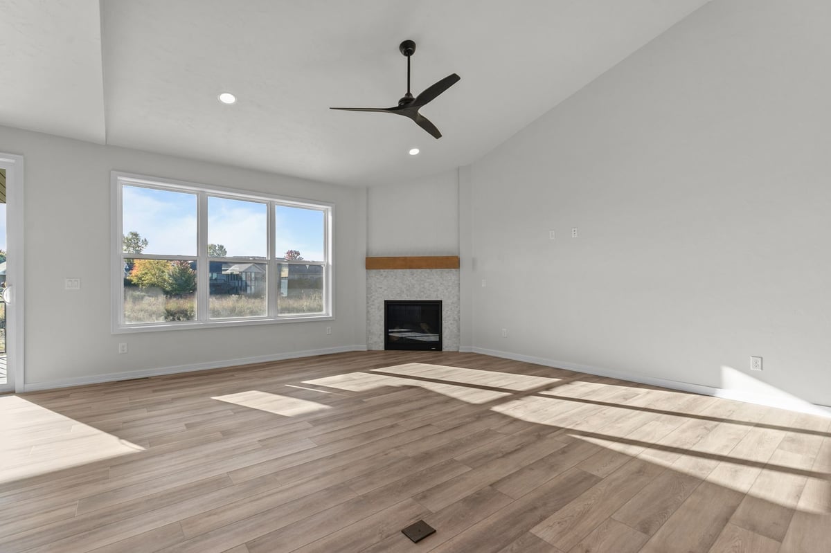 Appleton, WI bright living room with large windows, fireplace, ceiling fan, and wood flooring