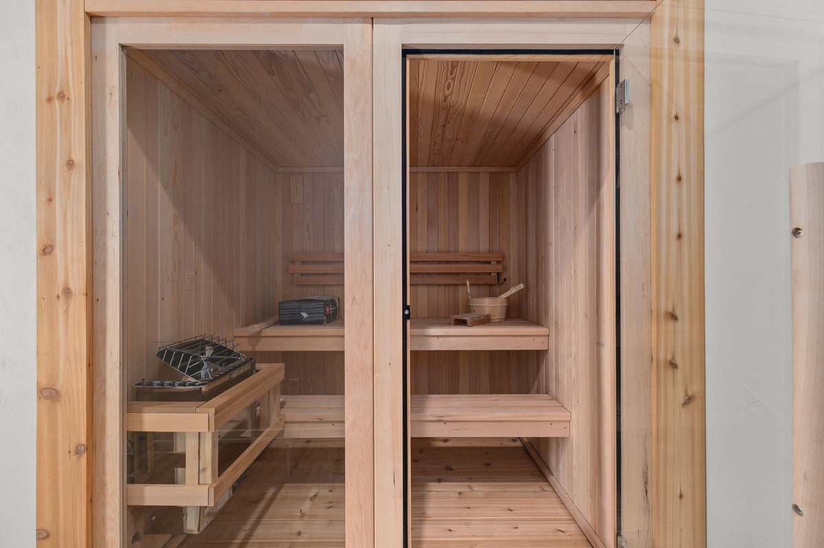 Appleton, WI cedar sauna interior with glass door, wood benches, heater, and bucket in a warm, spa-like setting