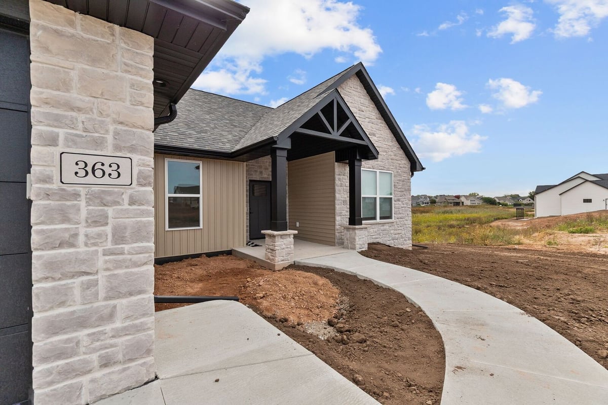 Appleton, WI front entry with stone columns, covered porch, and curved concrete walkway on unfinished landscaping