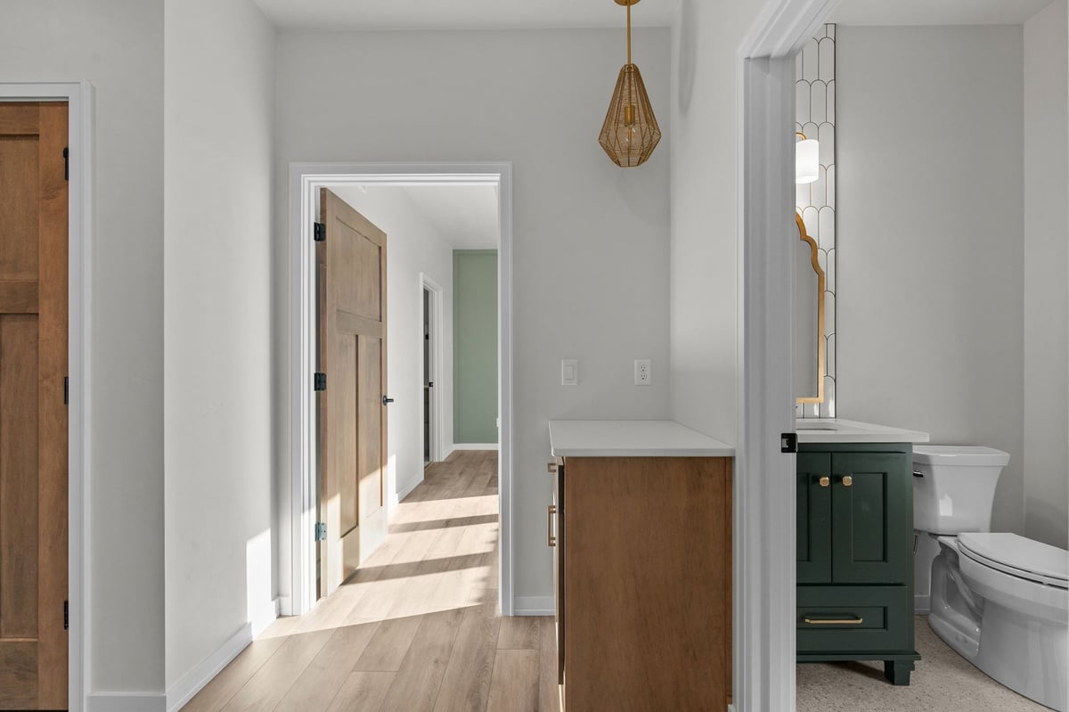 Appleton, WI hallway with wood doors, modern pendant light, and adjacent bathroom with green vanity