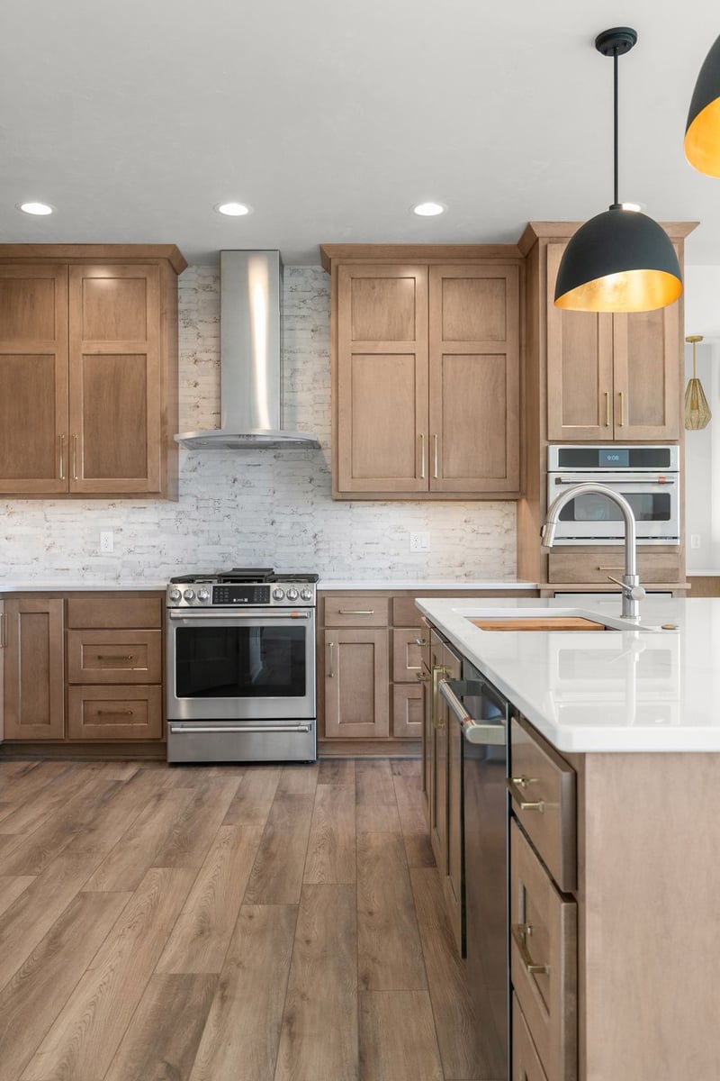 Appleton, WI kitchen with wood cabinetry, stainless range hood, large island, and pendant lighting