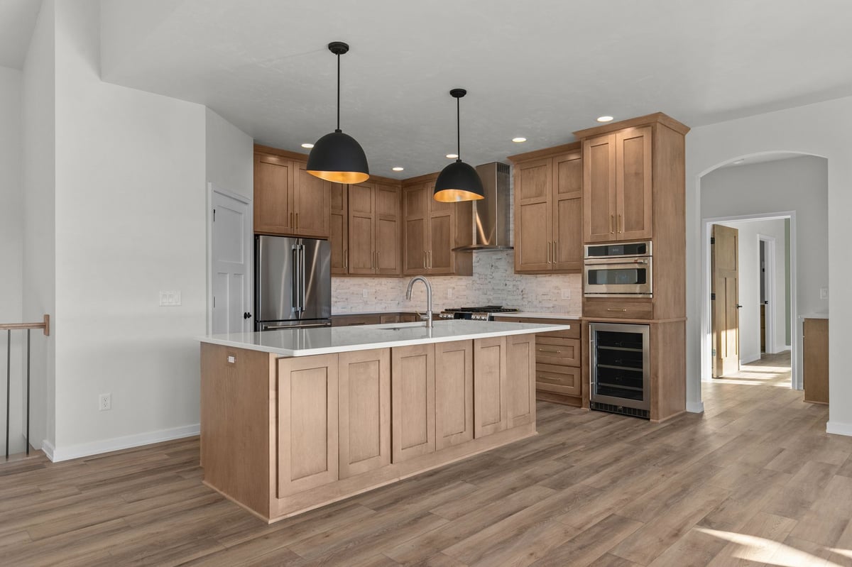 Appleton, WI modern kitchen with large island, wood cabinetry, pendant lights, stainless appliances, and open floor plan