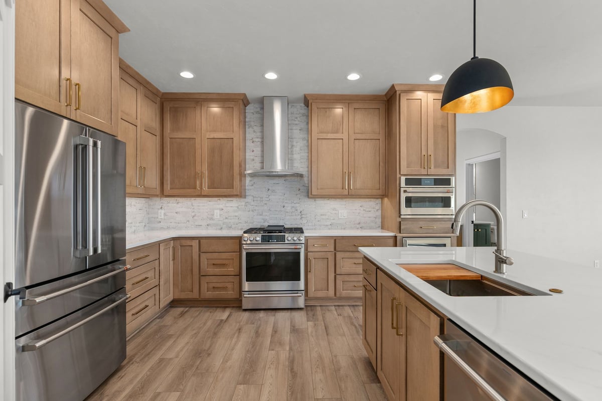 Appleton, WI modern kitchen with wood cabinets, white countertops, stainless appliances, and island with sink and pendant lighting