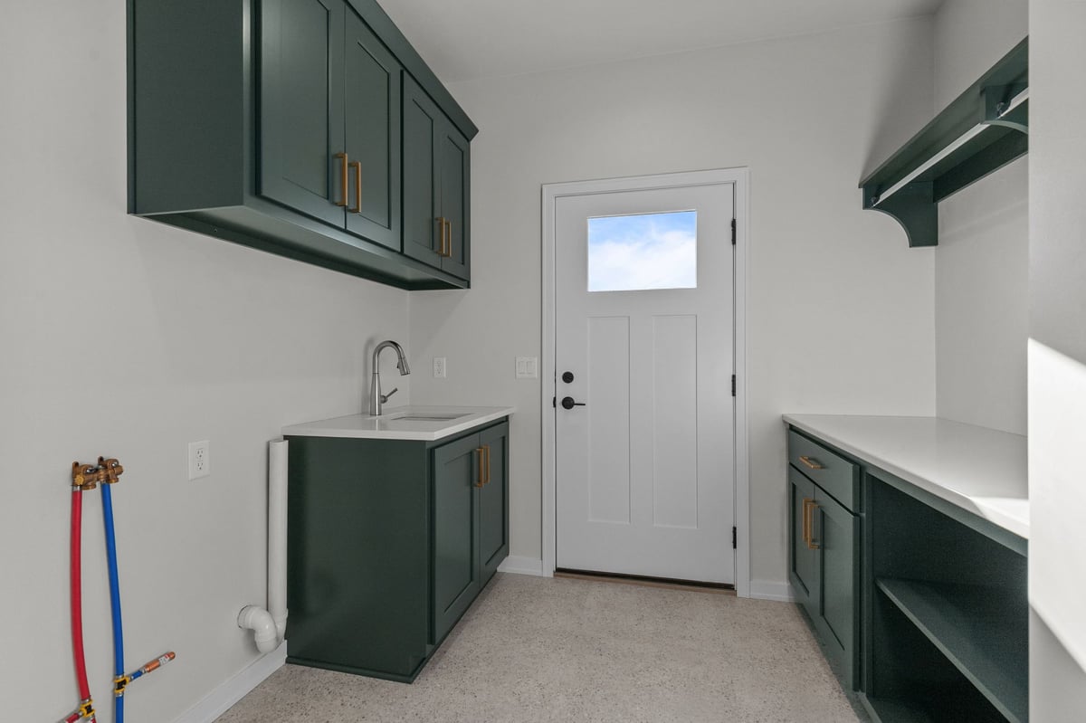 Appleton, WI mudroom with green cabinetry, utility sink, white door, and built-in storage