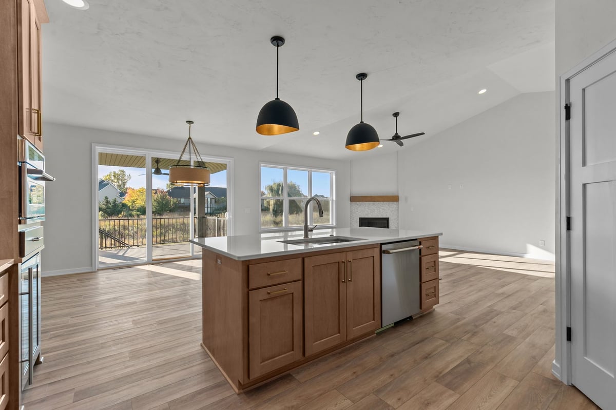 Appleton, WI open kitchen and living area with large island, wood cabinets, pendant lights, and sliding doors to deck