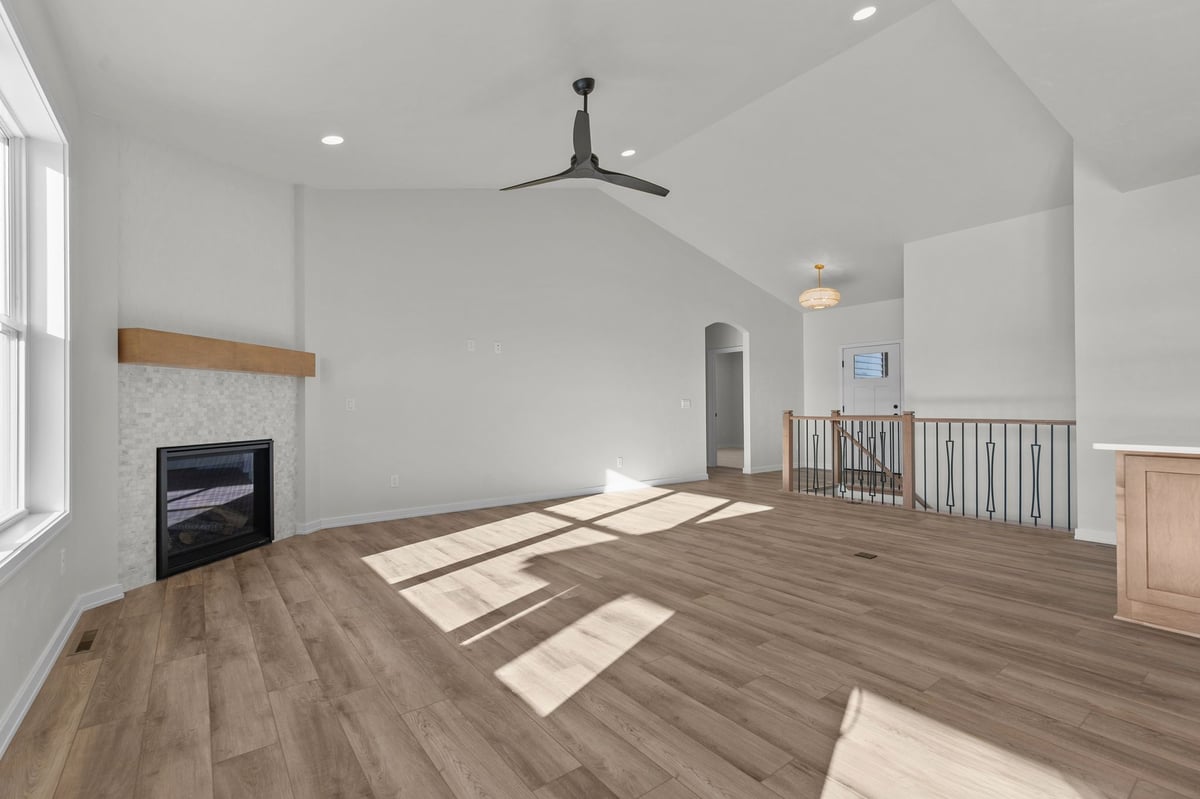 Appleton, WI open living area with fireplace, wood flooring, ceiling fan, and stair railing