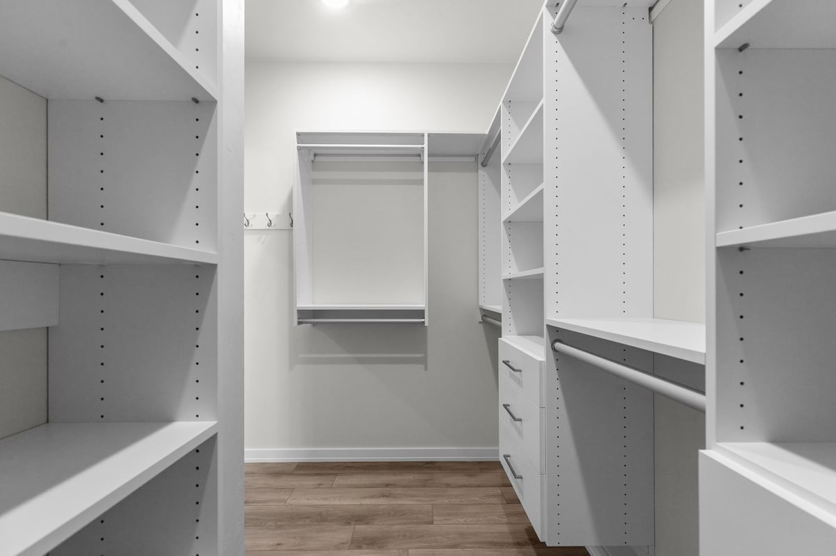 Appleton, WI walk-in closet with built-in white shelving, drawers, and hanging storage space