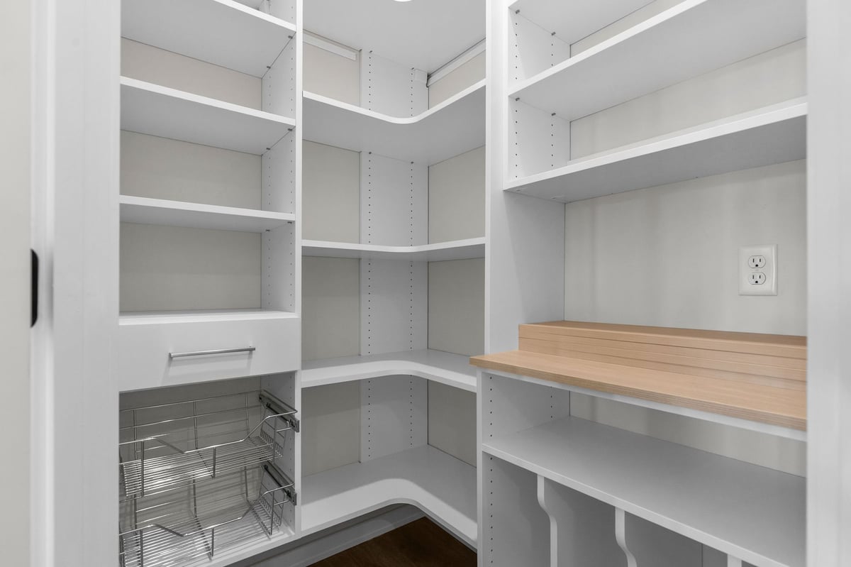 Appleton, WI walk-in pantry with white shelving, wire baskets, and wood countertop workspace