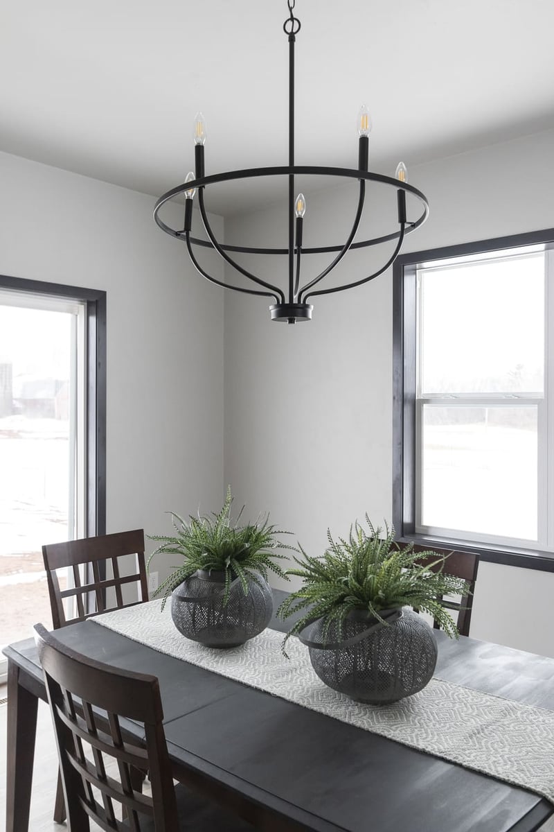 Dining room with dark wood table, modern black chandelier, and large windows in a Fox Cities home