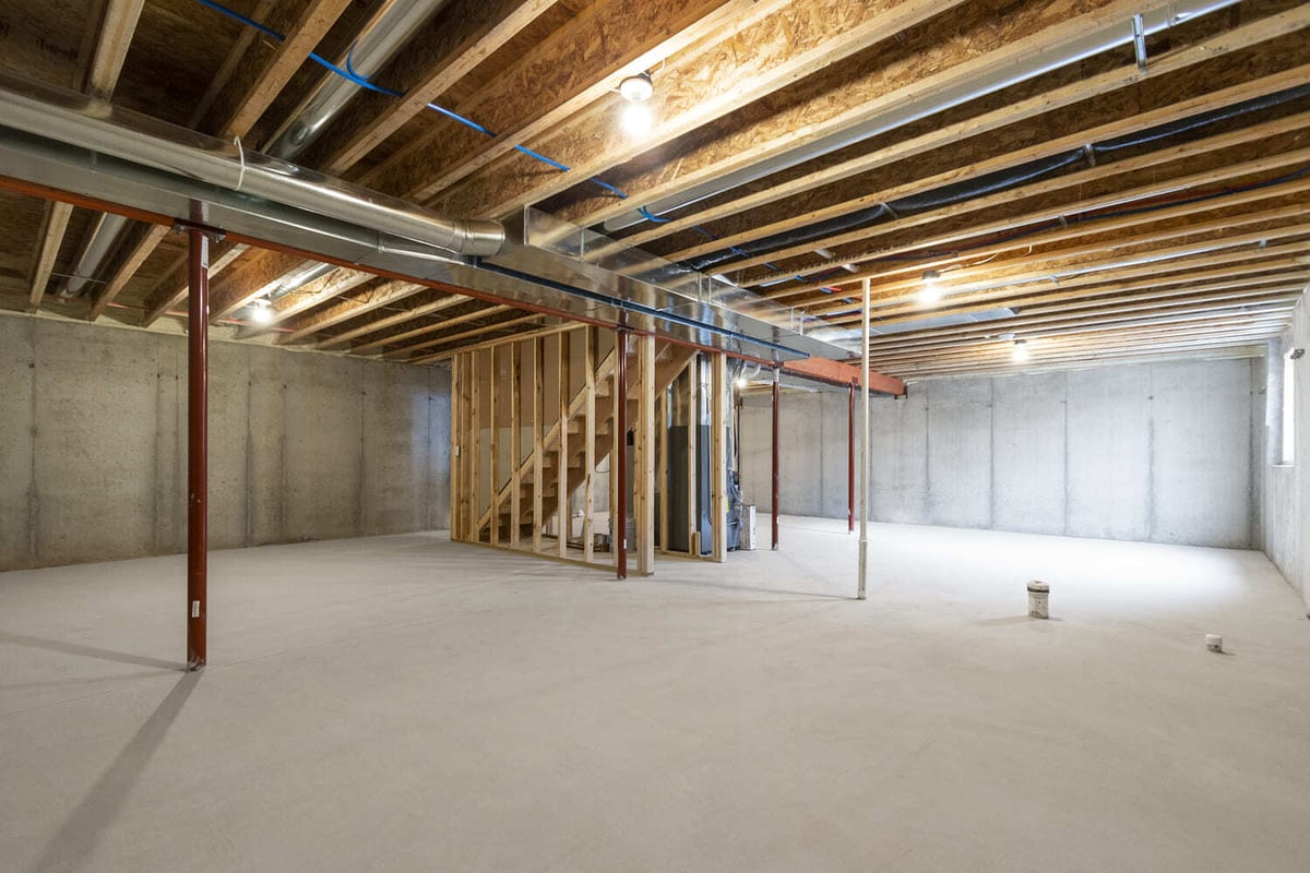 Large unfinished basement with exposed wood beams and stairs in the Fox Cities