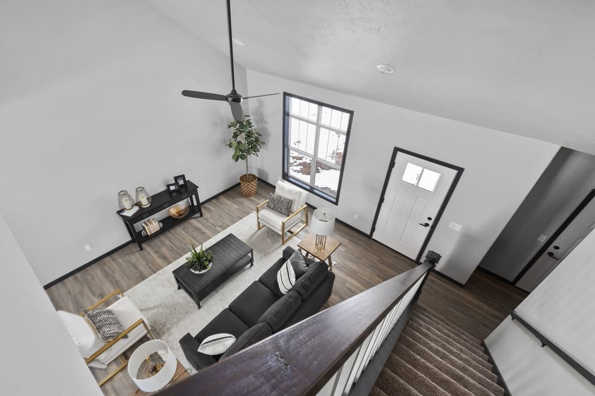 Living room view from staircase with modern furniture, ceiling fan, and entry door in the Fox Cities