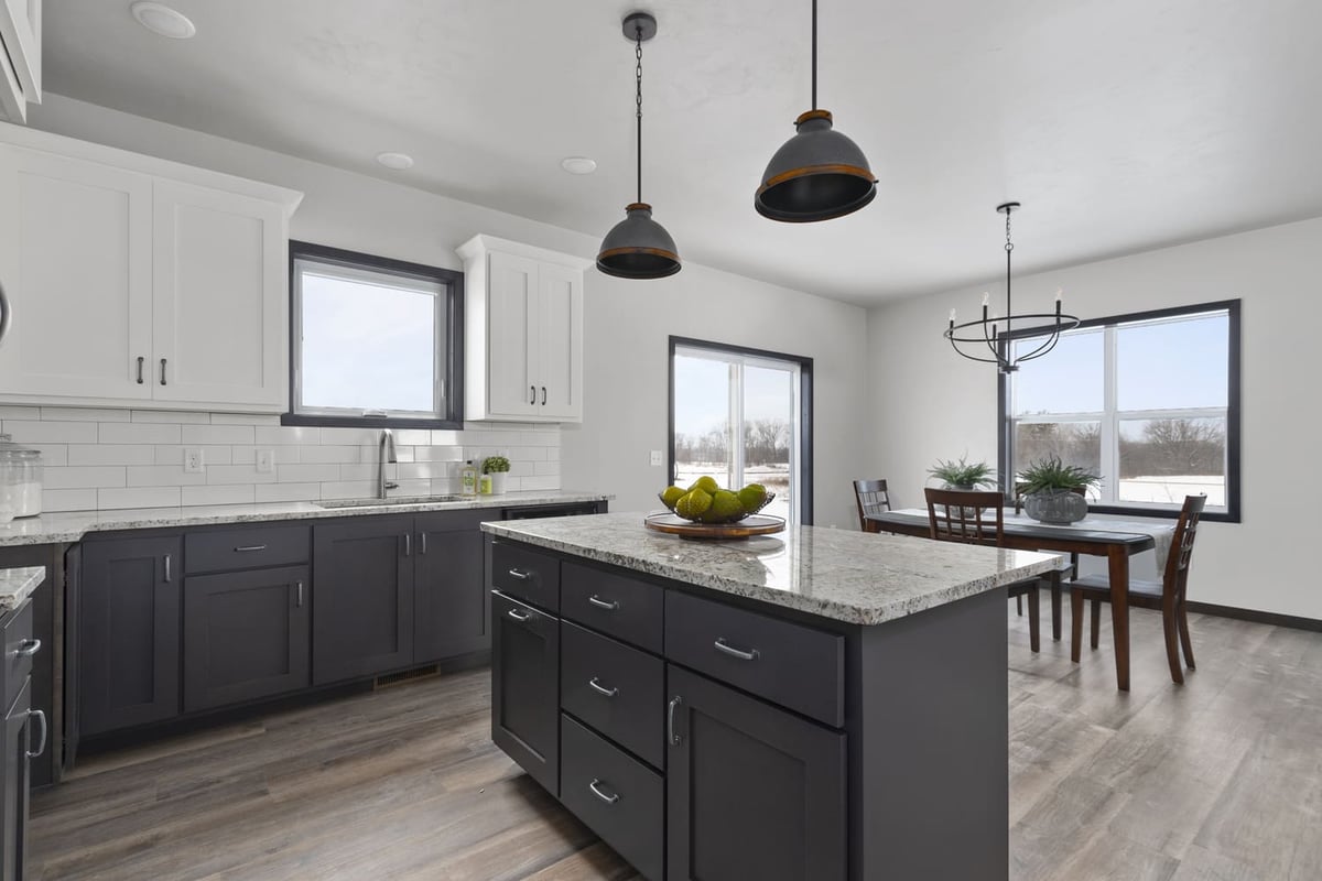 Modern kitchen with dark island, white cabinets, pendant lighting, and dining area in a Fox Cities home