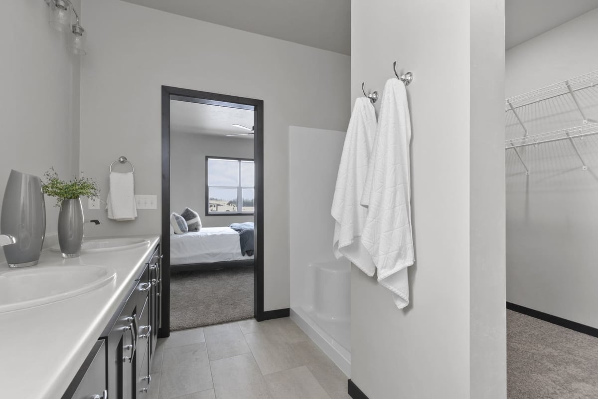 Primary bathroom with double vanity, tub shower, and walk-in closet access in a Fox Cities home