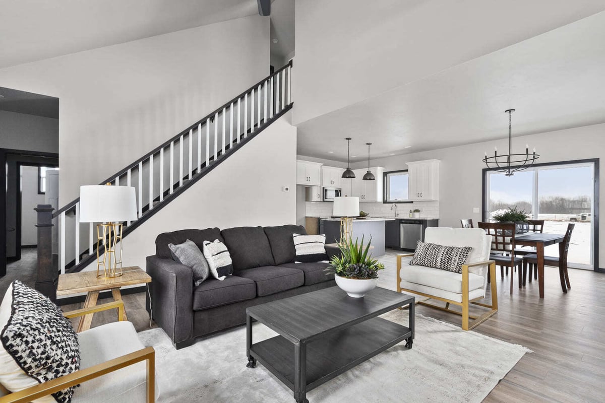Stylish living room featuring a dark sofa, white armchairs, and a modern staircase in the Fox Cities
