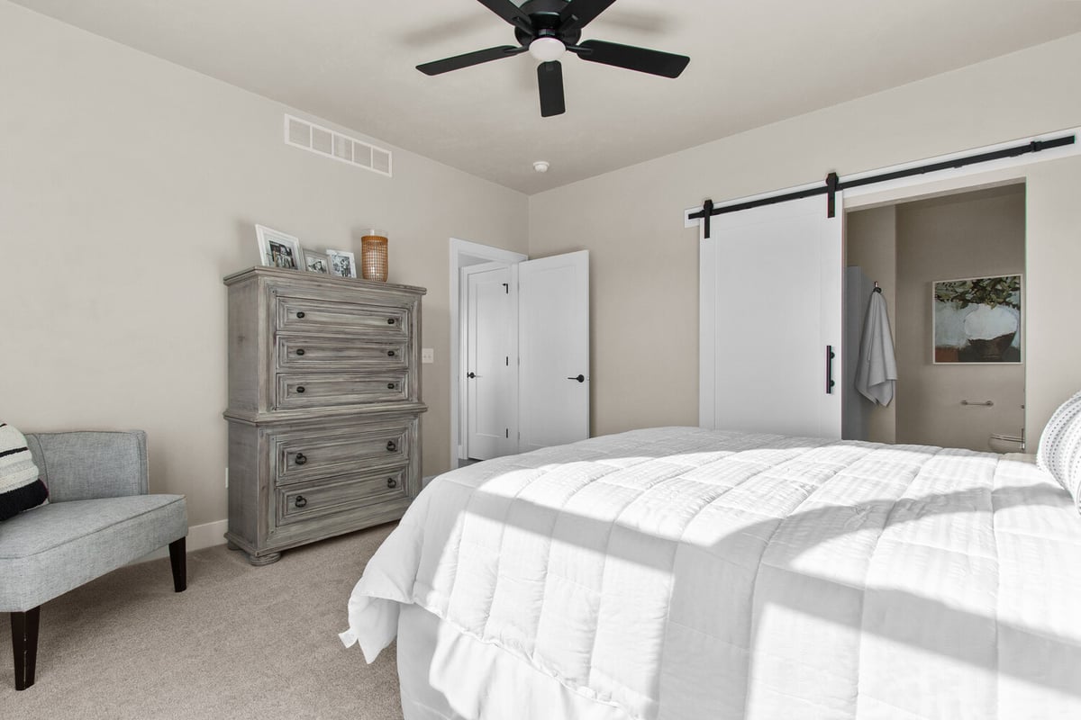 Bedroom with barn door entry to en suite bathroom by Midwest Design Homes in Harrison, WI