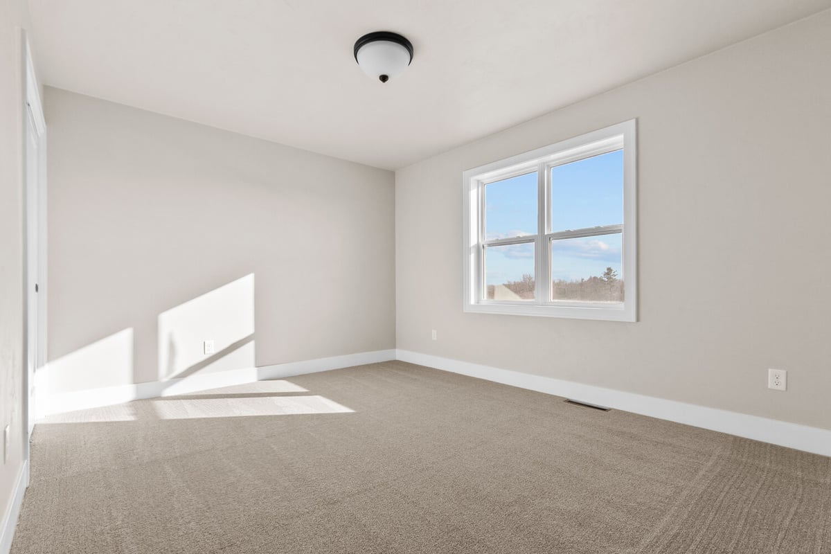 Bright bedroom with plush carpeting and closet space in a custom home by Midwest Design Homes in Harrison, WI