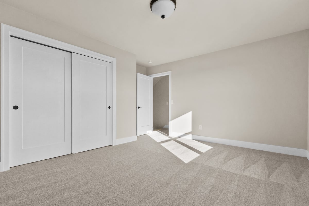 Bright carpeted bedroom with sliding closet doors in a Midwest Design Homes custom home in Kaukauna, WI