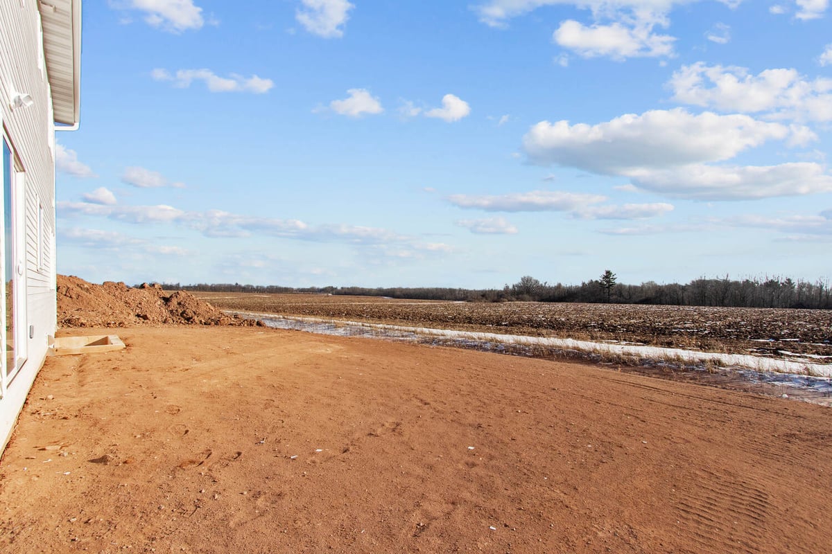 Side exterior landscape of a custom home by Midwest Design Homes overlooking rural land in Ellington, WI