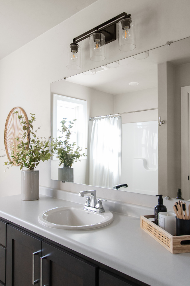Single-sink vanity with dark cabinetry in custom bathroom by Midwest Design Homes in Ledgeview, WI
