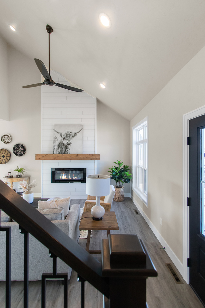Tall ceiling living room with fireplace and ceiling fan in a Midwest Design Homes custom home in Greenville, WI