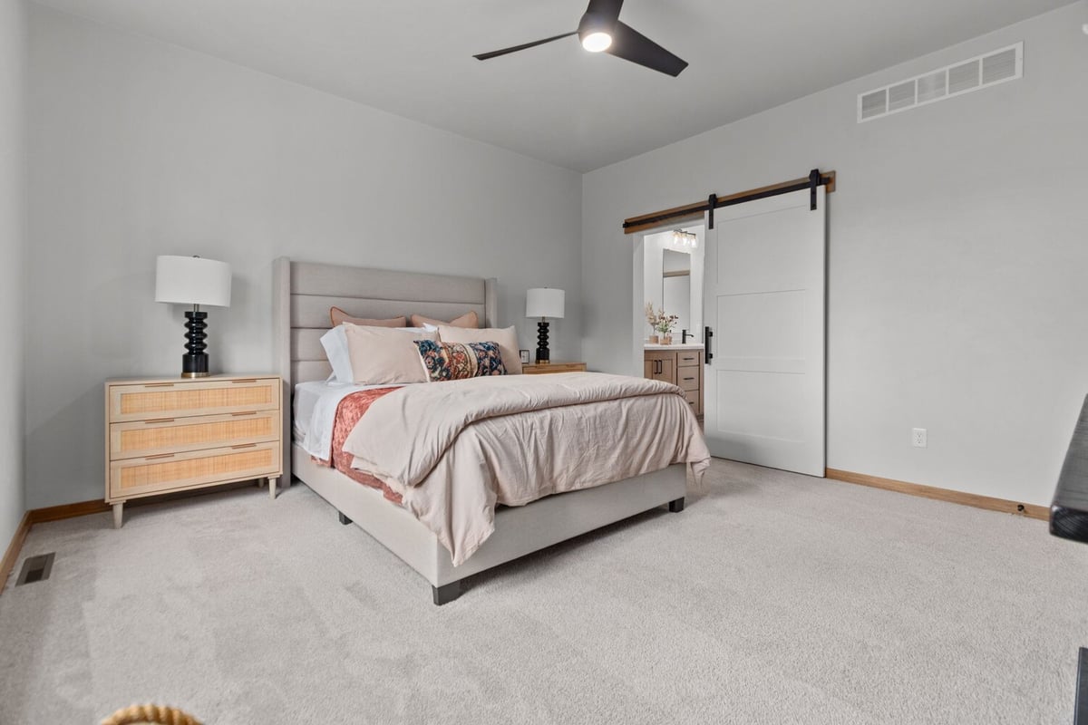 Master bedroom with upholstered bed and view into bathroom by Midwest Design Homes in Appleton, WI