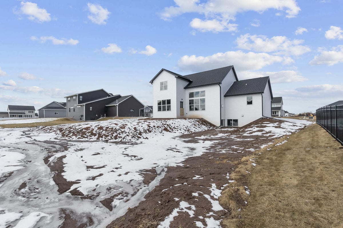 Backyard view of a new home in the Fox Cities with snow-covered ground and neighboring houses in the background