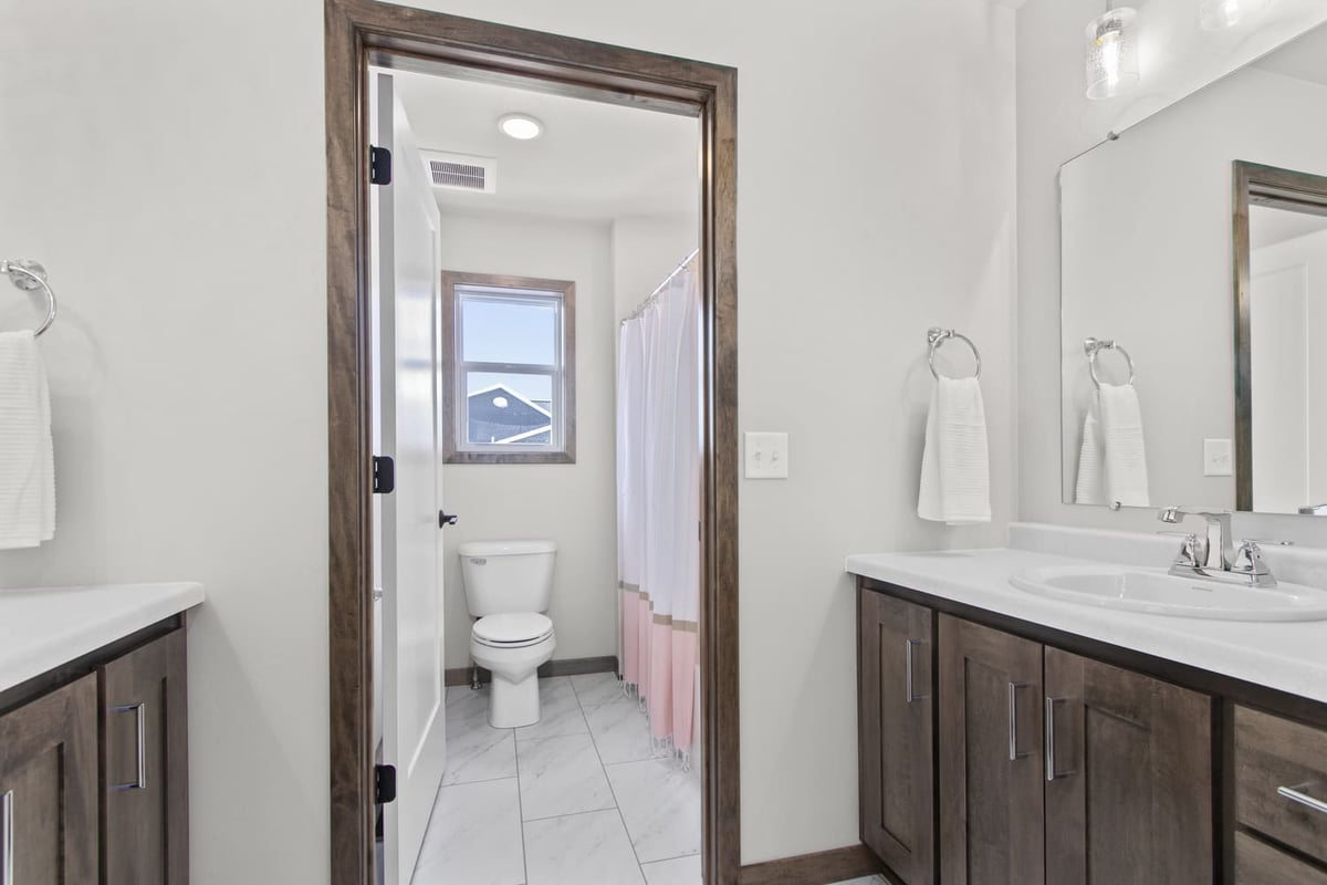Bright bathroom in the Fox Cities with wood cabinets, dual sinks, and private toilet area
