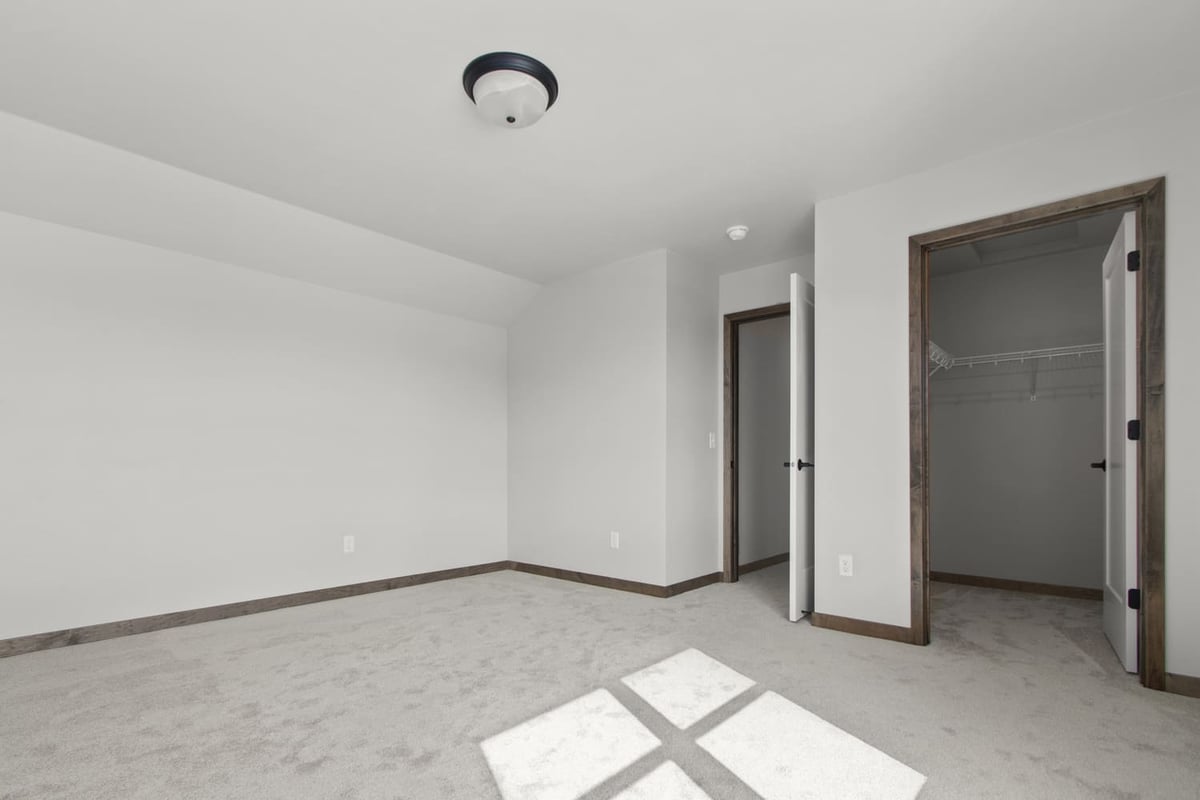 Bright carpeted bedroom in the Fox Cities with open closet doors and natural light from a large window