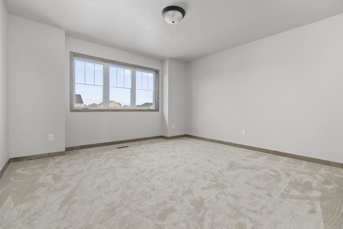 Empty carpeted bedroom with large window in a Fox Cities home
