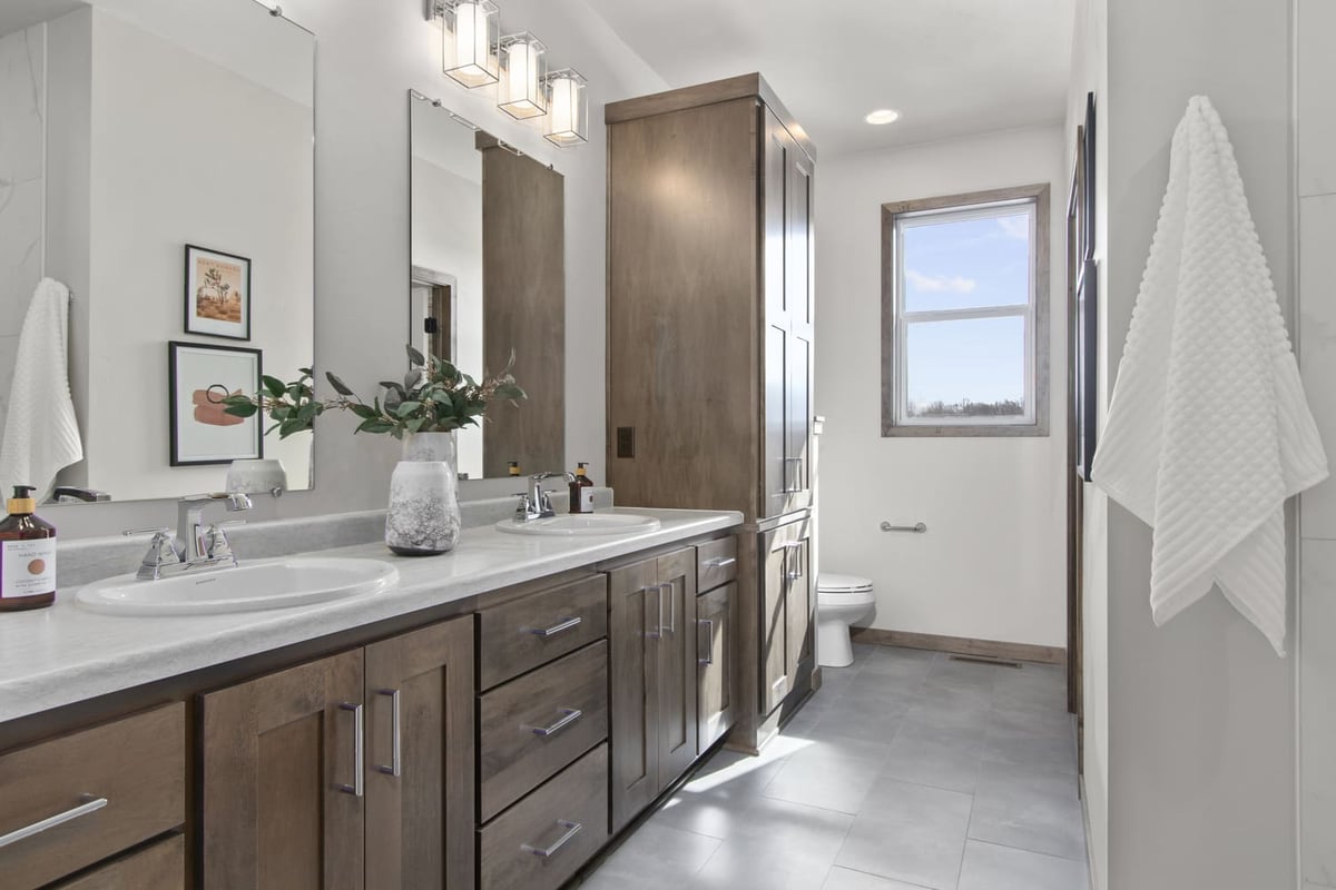 Fox Cities bathroom with double sinks, wood cabinetry, and modern lighting and decor
