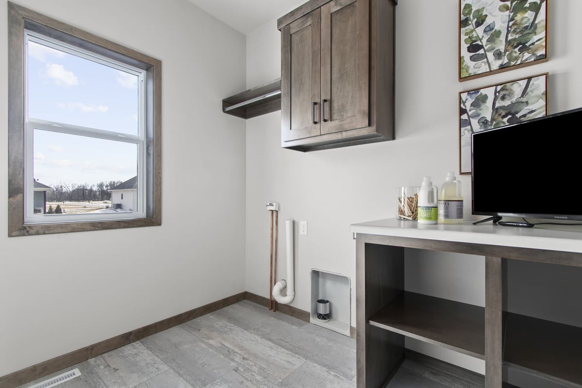 Laundry room in the Fox Cities with upper cabinets, folding space, and a large window