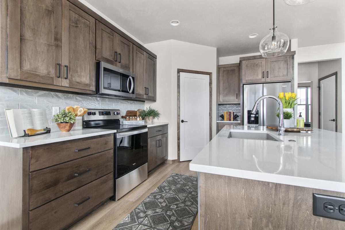 Modern kitchen in the Fox Cities featuring wood cabinetry, quartz countertops, stainless appliances, and pendant lighting over island