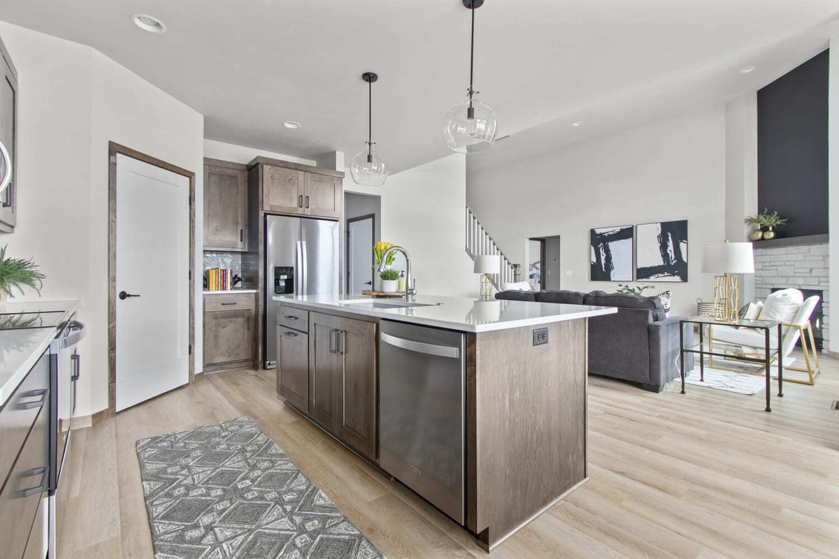 Modern kitchen with island and pendant lights overlooking open living space with fireplace, located in the Fox Cities