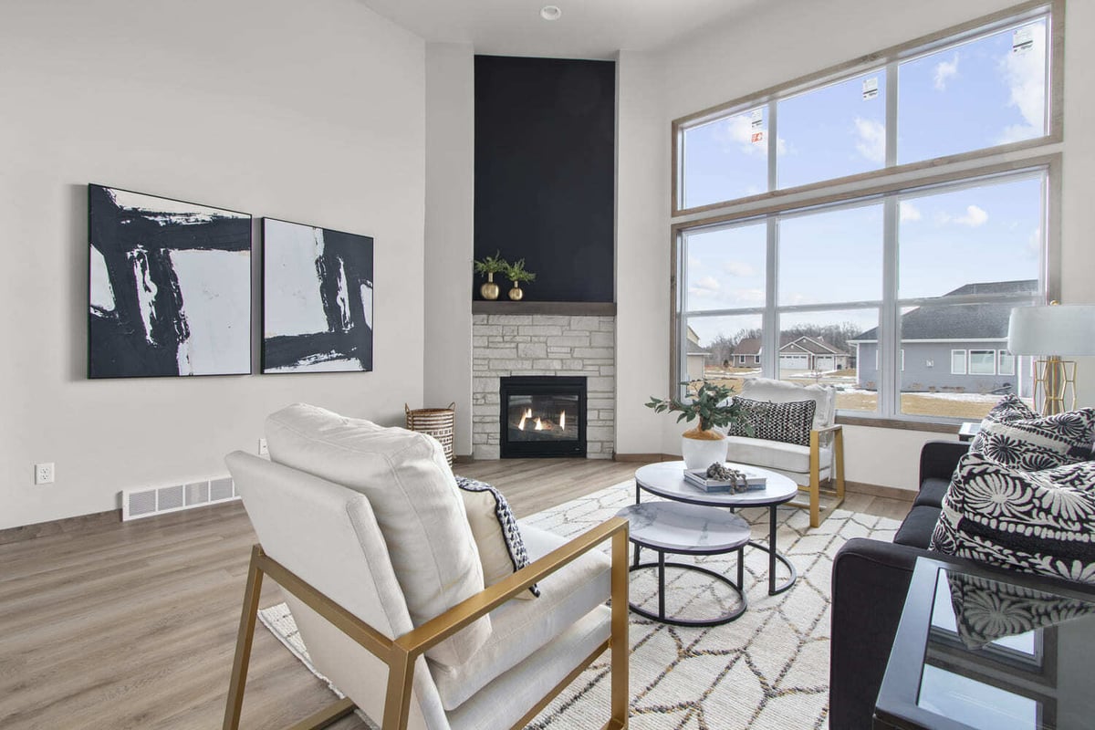 Modern living room in the Fox Cities with large windows, abstract art, and a corner fireplace with stone surround