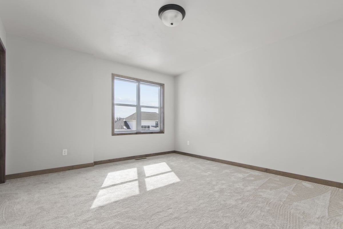 Spacious Fox Cities bedroom with soft carpeting, neutral palette, and large window letting in natural light