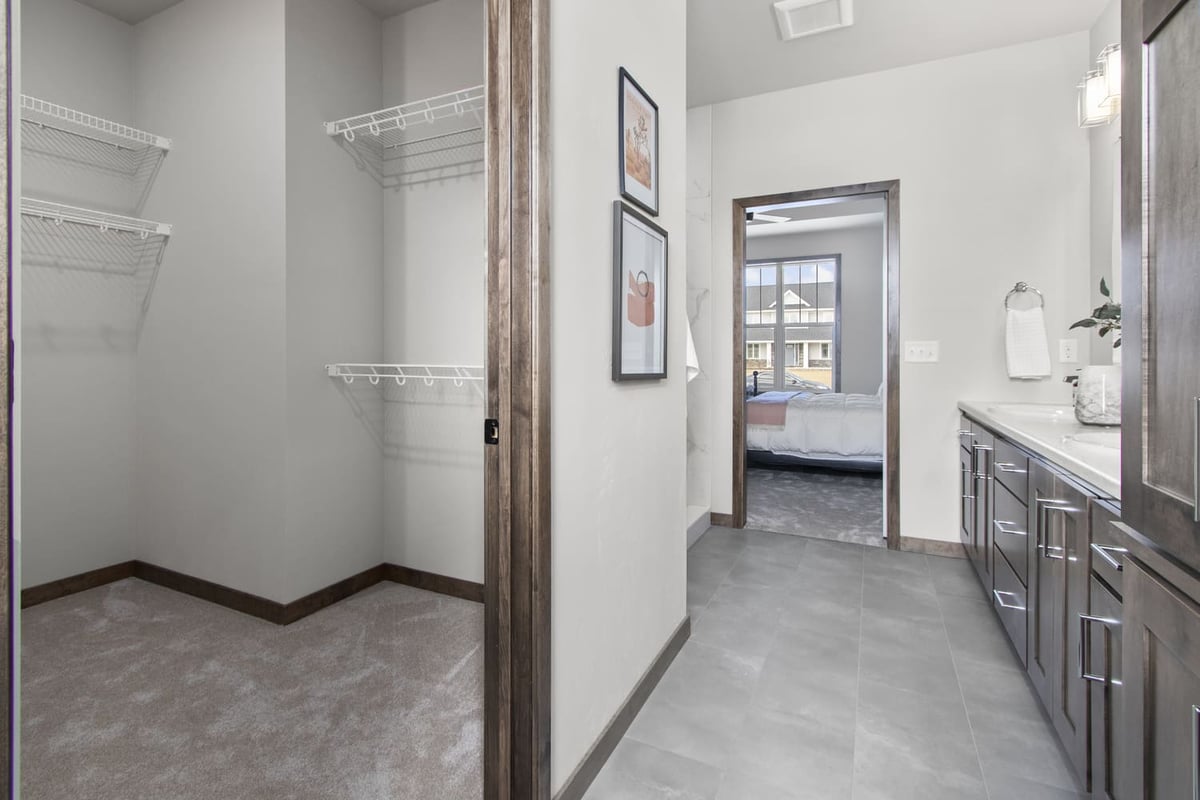 Spacious walk-in closet and bathroom in a Fox Cities home featuring tile floors and wood trim