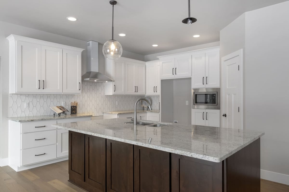 Bright kitchen with white cabinets, hex tile backsplash, stainless hood, and large island in a Fox Cities home