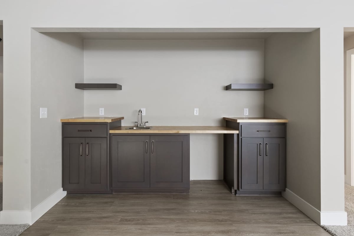 Built-in wet bar with dark cabinetry, wood countertops, and open shelving in a Fox Cities home