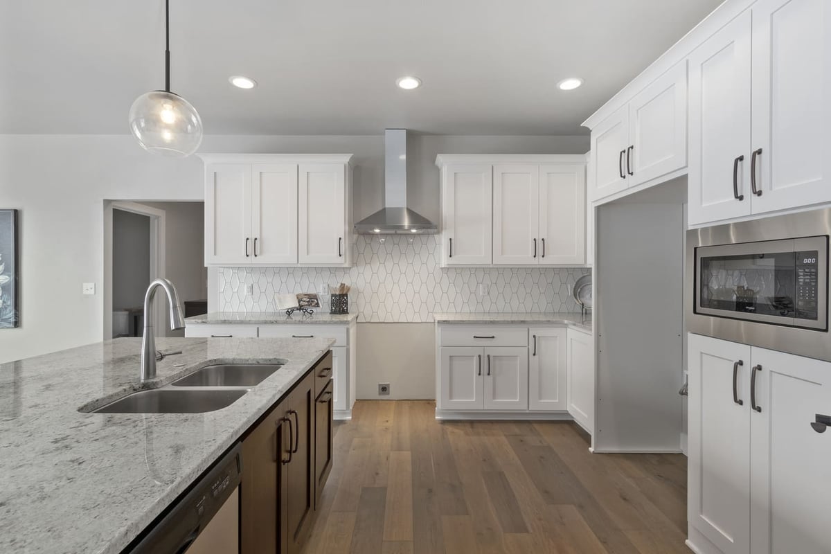 Clean white kitchen with built-in microwave, hex backsplash, and spacious island in a Fox Cities home