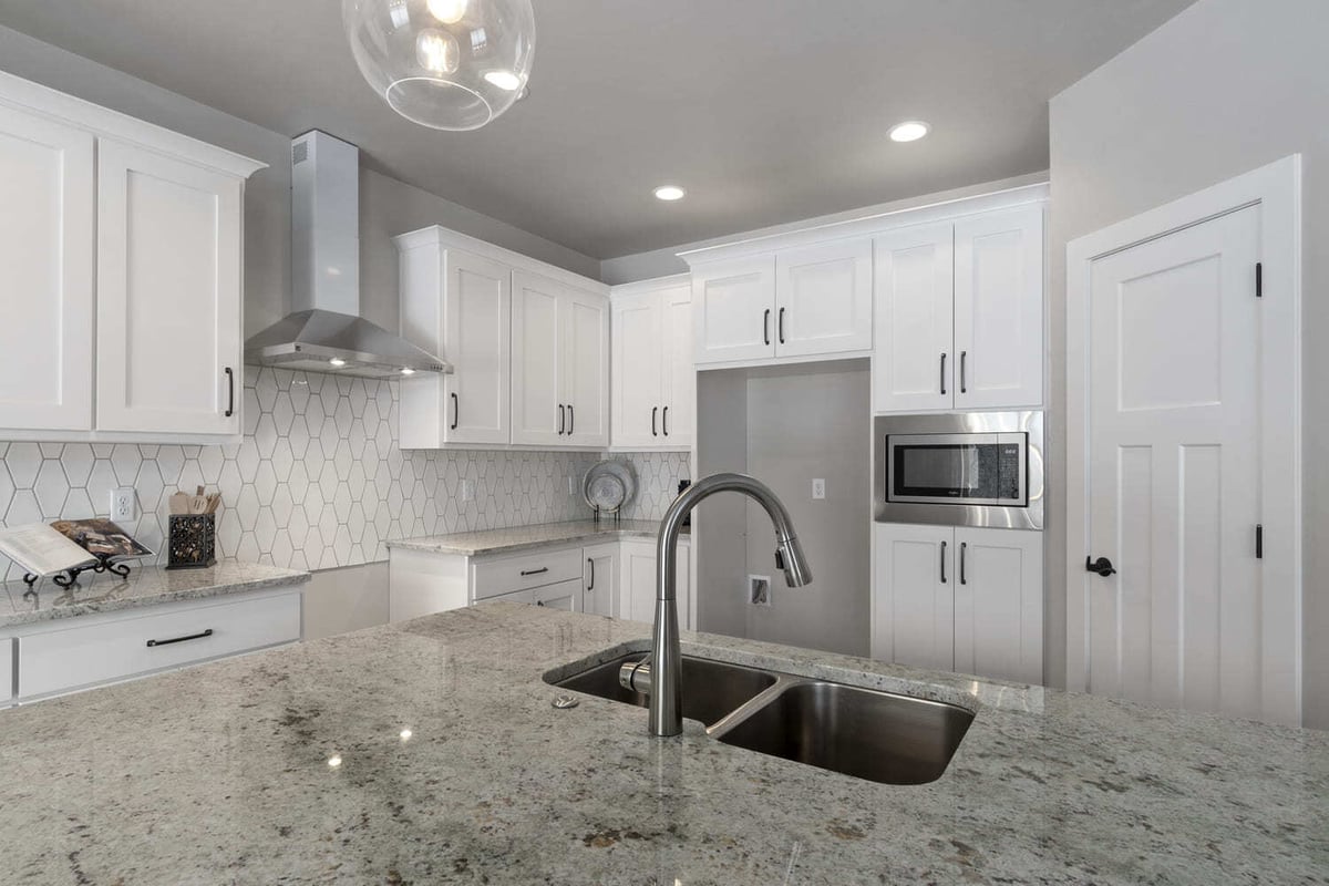 Kitchen island with granite countertop, undermount sink, and stainless faucet in a Fox Cities new construction home