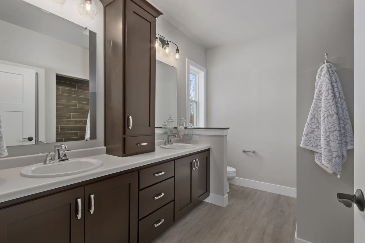 Modern bathroom with double-sink vanity, dark wood cabinets, and neutral finishes located in the Fox Cities