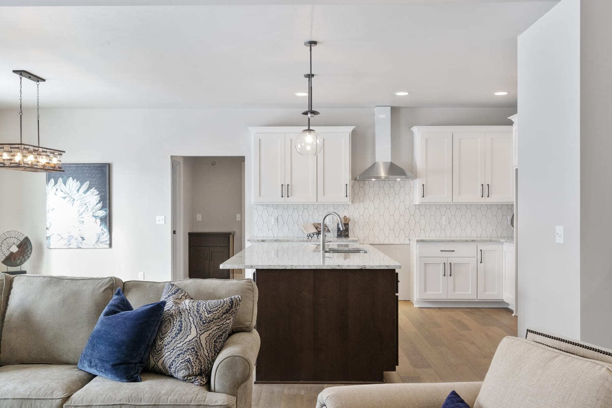 Open-concept Fox Cities kitchen with white cabinets, hex tile backsplash, and large island with dark wood base