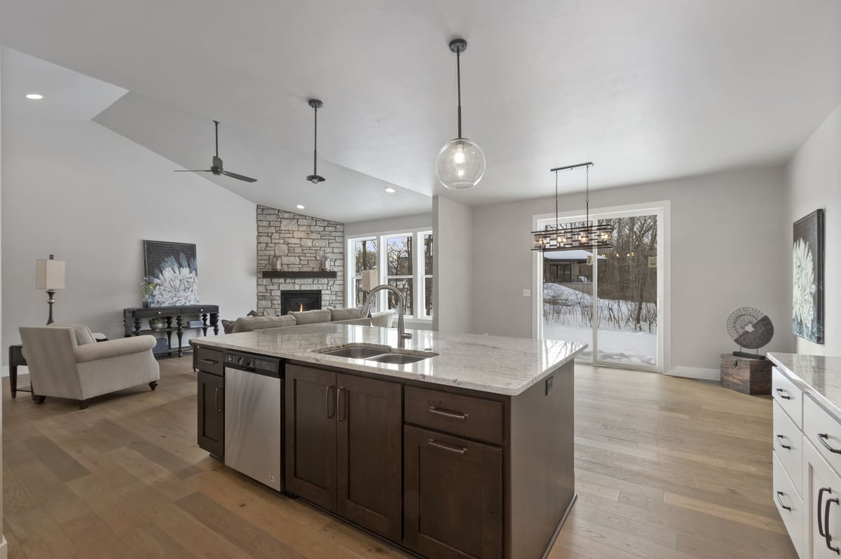 Open-concept kitchen and living area with large island, pendant lights, and fireplace in a Fox Cities home