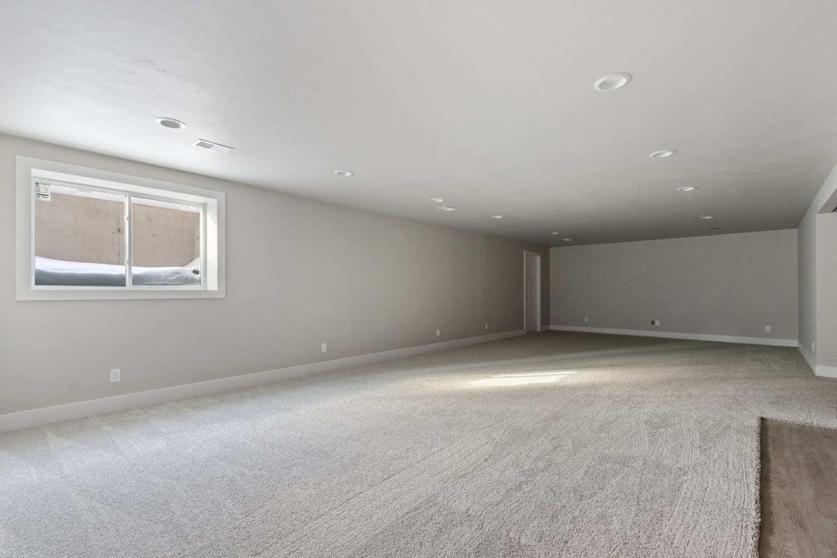 Spacious finished basement with carpeted floors, recessed lighting, and daylight window in a Fox Cities home