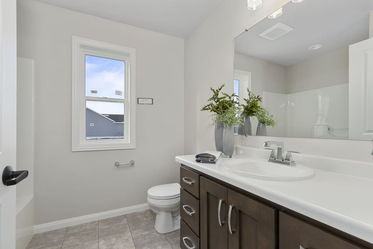 Bathroom with single-sink vanity, large mirror, window, and neutral tile flooring in a Fox Cities home