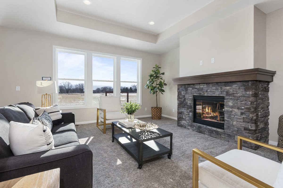 Bright living room with stone fireplace, large windows, and neutral finishes in a Fox Cities home