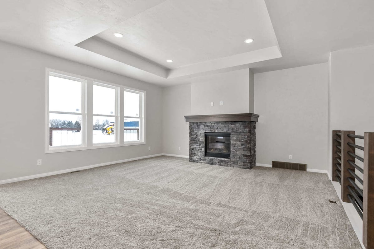 Bright living room with stone fireplace, tray ceiling, and large windows in a Fox Cities home