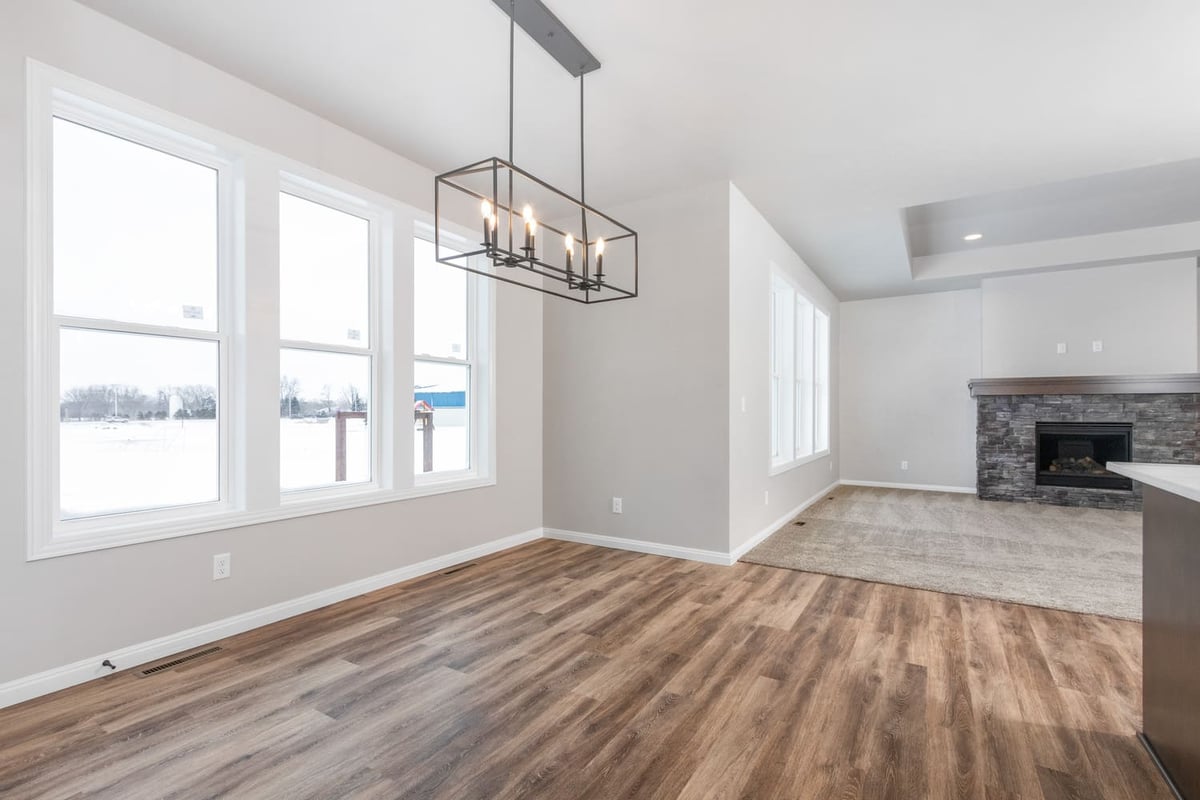 Dining area with modern rectangular chandelier, large windows, and wood flooring in a Fox Cities home
